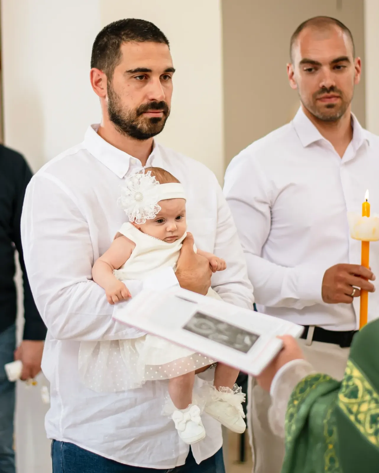 Tata sa bebom u naručju tokom obreda krštenja