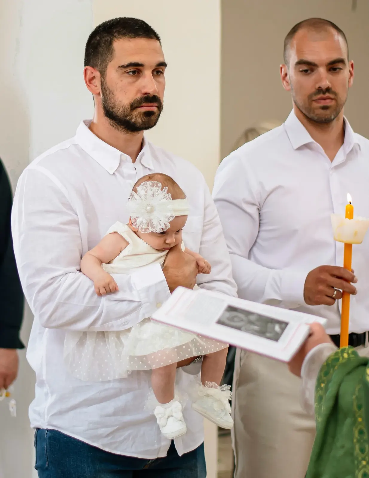 Kuma dodaje krštenjsku sveću tokom obreda u crkvi
